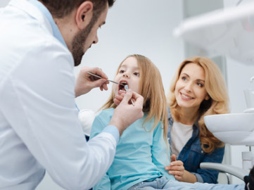 A dentist examining a child’s mouth