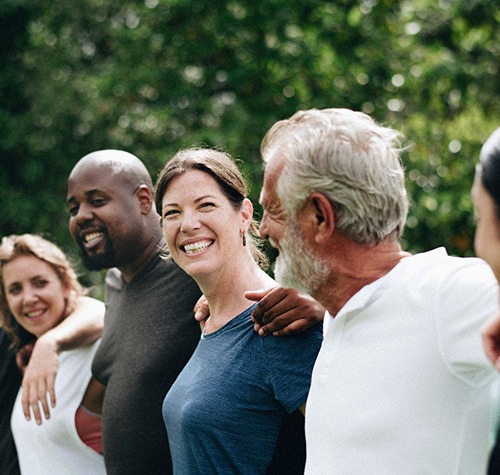 Smiling Norwood patient showing new dental implants with friends
