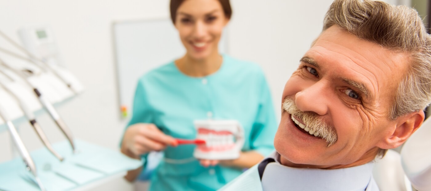 Senior man smiling in dental chair with dentures in Norwood