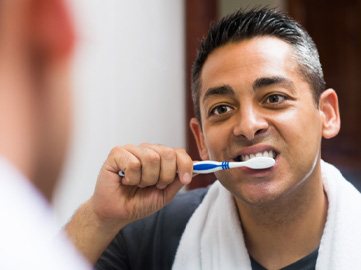Man brushing his dental implants in Norwood