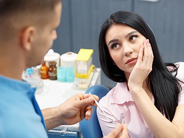 Woman with toothache looking at dentist during appointment