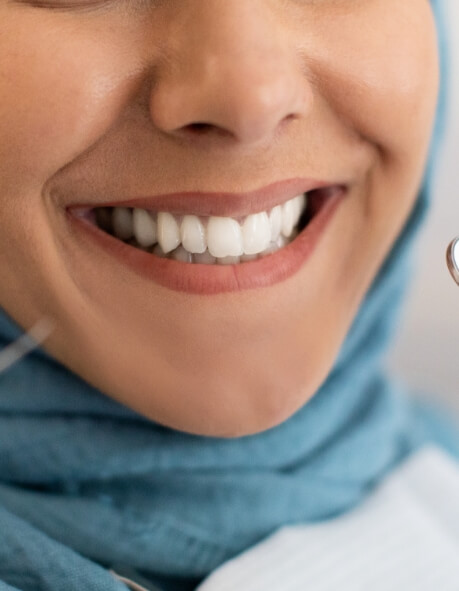 Woman in dental chair with shade guide next to mouth.