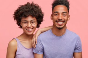 couple smiling against pink background