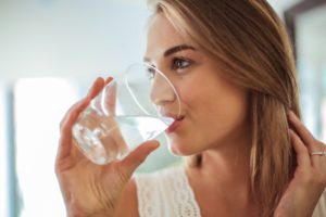 woman drinking water to combat dry mouth