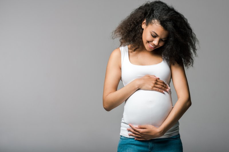 pregnant person smiling and holding belly