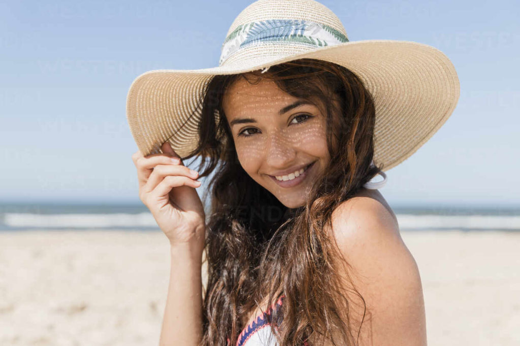 person smiling on beach after undergoing teeth whitening